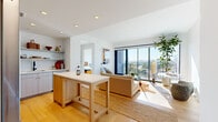 Located in Nashville's vibrant 37208 corridor, this modern two-bedroom, two-bathroom residence offers a thoughtfully designed single-level layout that maximizes both comfort and style. Light hardwood flooring flows throughout, anchoring the open-concept kitchen and living area in a warm, cohesive aesthetic.

The kitchen is outfitted with sleek grey shaker-style cabinetry extending to the ceiling, white quartz countertops, stainless steel appliances including a gas range and French door refrigerator, and a light wood island that doubles as a casual dining and prep space. Open shelving adds a curated, functional touch.

The living room is bathed in natural light courtesy of expansive floor-to-ceiling windows and a sliding glass door that opens to a private balcony, offering panoramic views of the Nashville skyline. The primary bedroom continues this elevated design with a striking full-height grid window framing sweeping city views, a dedicated closet, and clean white walls that emphasize the airy feel. The second bedroom is equally well-appointed with a built-in closet and generous natural light.

The bathrooms feature warm wood vanities with black hardware accents, white quartz countertops, and terrazzo-style tile flooring. A dedicated walk-in closet provides additional storage. The overall ambiance is contemporary, light-filled, and urban.
