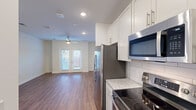 Located at 2110 Birkhall St in Raleigh, NC, this efficiently designed single-floor unit makes excellent use of its space through a thoughtful, open layout. Rich hardwood-style flooring flows throughout, tying each area together with a warm, cohesive aesthetic.

The galley kitchen is a standout feature, outfitted with crisp white shaker cabinetry, granite-patterned countertops, a classic subway tile backsplash, and a full suite of stainless steel appliances including a side-by-side refrigerator with water dispenser, electric range, over-the-range microwave, and dishwasher. A pantry provides additional storage, keeping the kitchen organized and functional.

The open living area is bright and airy, illuminated by recessed lighting and a ceiling fan, with natural light streaming in through French doors that lead to a private balcony — offering a pleasant outdoor extension of the living space.

The bathroom is clean and modern, featuring a glass-enclosed walk-in shower with white subway tile surround and wood-look flooring that continues the unit's consistent design language. Two closets and a utility room provide ample storage and practical functionality. The entrance sets a welcoming tone, completing a unit that balances comfort, style, and efficiency.