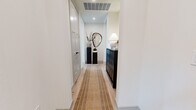 This thoughtfully designed 2-bedroom, 4-bathroom residence offers a refined living experience across a single, well-appointed floor. The open-concept living and kitchen area serves as the heart of the home, anchored by dramatic floor-to-ceiling windows that flood the space with natural light and frame sweeping city views. The living room features light hardwood flooring, a contemporary chandelier, and a seamless flow into the kitchen, which is outfitted with white shaker cabinetry, a sage green tile backsplash, stainless steel appliances, a wine refrigerator, and a generously sized island with seating. The entryway hallway is elegantly appointed with light wood flooring, a woven runner, and curated decor, creating a welcoming arrival experience. The spacious primary bedroom features built-in bookshelves, a structural concrete column accent, and large windows with city views, complemented by a dedicated walk-in closet with adjustable wire shelving. The secondary bedroom offers carpeted flooring, a window with natural light, and a built-in workspace. The bathrooms are finished with marble-look tile flooring, slate-blue cabinetry, white quartz countertops, and wall sconce lighting, delivering a consistent, upscale aesthetic throughout the residence.