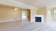 This four-story townhome in Seven Fields, PA offers a well-organized layout across multiple levels, providing ample space for comfortable living. The ground floor features an attached garage with a utility room, offering convenient storage and direct interior access. The main living level serves as the heart of the home, highlighted by a spacious living room with a classic fireplace, crown molding, and a ceiling fan, seamlessly connecting to a dining area illuminated by a chandelier. The kitchen is equipped with warm oak cabinetry, hardwood-style flooring, stainless steel appliances, and generous counter space. The upper bedroom level houses multiple carpeted bedrooms, each with closets and access to well-appointed bathrooms featuring wood vanities, white tub-shower combinations, and hardwood flooring. The top floor is dedicated to the expansive primary suite, which boasts vaulted ceilings, a ceiling fan, dual closets, natural light from a window, and a private en-suite bathroom. The lower level includes an additional carpeted room ideal for flexible use. Warm neutral tones and plush carpeting throughout create a cohesive and inviting ambiance in this thoughtfully designed multi-level townhome.