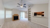 This efficiently designed single-story residence offers a thoughtful layout across a comfortable footprint, with distinct living areas that maximize functionality. The open-concept living and dining room serves as the heart of the home, highlighted by soaring vaulted ceilings, a ceiling fan with light fixture, and a tile-surround fireplace that adds warmth and character. Built-in shelving flanks a pass-through opening to the kitchen, enhancing both storage and visual flow. A sliding glass door floods the space with natural light and provides access to the outdoors. The kitchen features rich warm-toned wood cabinetry, a stone mosaic tile backsplash, light countertops, and black appliances including a refrigerator, gas range, dishwasher, and built-in microwave, all set on durable wood-look flooring. The spacious bedroom offers plush carpeting, a ceiling fan, a natural light window, and ample closet space. Three closets throughout the unit, including a walk-in with built-in shelving and rod storage, provide generous organization options. The bathroom includes a full tub-shower combination with clean white tile surround. Hallways connect the spaces efficiently, completing this well-structured and comfortable single-level home.