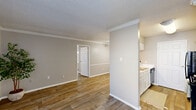 Located at 5636 Spring Valley Rd in Dallas, TX, this single-floor residence offers a practical and comfortable layout with 2 bedrooms and 2 bathrooms. The open-concept living, dining, and kitchen area forms the heart of the home, unified by warm wood-look flooring and neutral gray walls accented by crisp white crown molding and baseboards. A textured ceiling adds character throughout the main living space. The kitchen features a pass-through design with white cabinetry, marble-style countertops, a black refrigerator, and an electric range, providing an efficient and stylish cooking environment. Both bedrooms are well-proportioned, each equipped with ceiling fans and generous closet space — including a walk-in closet with built-in shelving and hanging rods in the primary bedroom. The second bedroom benefits from a window that brings in natural light. Both bathrooms include tub/shower combos with clean white tile surrounds. Additional conveniences include a dedicated laundry area, multiple closets for ample storage, and a hallway connecting the private areas of the home. The cohesive, neutral palette and updated finishes throughout create a clean, move-in-ready atmosphere well-suited for comfortable everyday living.