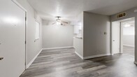 This efficiently designed single-floor unit offers a practical and comfortable layout across one bedroom, one bathroom, a living room, and a closet. The living area is finished with durable wood-look plank flooring in a warm gray tone and features a ceiling fan with a light fixture. Neutral gray walls and white baseboards throughout lend a clean, modern aesthetic. A pass-through counter connects the living space to the kitchen, which is equipped with white cabinetry and a freestanding range, making the most of the available footprint.

The bedroom continues the same wood-look flooring and neutral palette, with a ceiling fan overhead and a window fitted with blinds that allows natural light to filter in. A dedicated closet provides convenient storage. The full bathroom is finished with large-format earthy tile on both the walls and floor, surrounding a full soaking tub and shower combination with a brushed nickel fixtures. A standard toilet completes the bathroom layout.

Overall, the space presents a cohesive and tidy interior with consistent finishes throughout, offering a functional and low-maintenance living environment well-suited for individuals or couples seeking a straightforward, single-level layout.