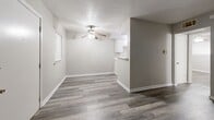 This efficiently designed single-floor unit offers a practical and comfortable layout across one bedroom, one bathroom, a living room, and a closet. The living area is finished with durable wood-look plank flooring in a warm gray tone and features a ceiling fan with a light fixture. Neutral gray walls and white baseboards throughout lend a clean, modern aesthetic. A pass-through counter connects the living space to the kitchen, which is equipped with white cabinetry and a freestanding range, making the most of the available footprint.

The bedroom continues the same wood-look flooring and neutral palette, with a ceiling fan overhead and a window fitted with blinds that allows natural light to filter in. A dedicated closet provides convenient storage. The full bathroom is finished with large-format earthy tile on both the walls and floor, surrounding a full soaking tub and shower combination with a brushed nickel fixtures. A standard toilet completes the bathroom layout.

Overall, the space presents a cohesive and tidy interior with consistent finishes throughout, offering a functional and low-maintenance living environment well-suited for individuals or couples seeking a straightforward, single-level layout.
