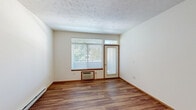 Located at 1821 E Calkins Ave in Spokane, WA, this single-floor, two-bedroom, two-bathroom unit offers a practical and well-organized layout. The living area is anchored by warm wood-look flooring that extends through the main living spaces and hallway, creating a cohesive and inviting atmosphere. A textured ceiling runs throughout, adding a classic residential character.

The kitchen is designed with efficiency in mind, featuring a raised peninsula counter that opens toward the living room, warm wood cabinetry, tile backsplash, light stone-tone countertops, and white appliances including a range, microwave, refrigerator, and dishwasher. The open sightline between the kitchen and living area makes the shared space feel connected and functional.

The living room benefits from natural light through large windows with blinds and offers direct outdoor access via a private exterior door — a notable feature for convenient entry or outdoor enjoyment.

Both bedrooms are carpeted and well-lit by windows overlooking greenery, providing a calm and comfortable atmosphere. Each bedroom is supported by its own closet. Baseboard heating is present throughout the bedrooms.

The bathrooms are clean and functional, with one featuring a full tub/shower combination, toilet, and vanity with mirror. A central hallway connects all rooms, maintaining a clear and efficient flow throughout the unit.