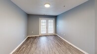 Located at 4013 Peaks Landing Way in Knoxville, Tennessee, this single-floor residence offers a well-organized layout designed for comfortable everyday living. The main living area is finished with durable wood-look flooring and is painted in cool, neutral blue-gray tones throughout, creating a cohesive and calming aesthetic. A standout feature of the living space is the set of French doors, which flood the room with natural light and provide access to the outdoors.

The kitchen is equipped with light wood cabinetry, white appliances including a refrigerator, range, and dishwasher, along with a double sink and white countertops. The space is practical and efficiently laid out, with ample cabinet storage above and below the counters.

The bedrooms feature plush wall-to-wall carpeting and windows overlooking green outdoor views, offering a quiet and comfortable retreat. Each room benefits from the consistent blue-gray color palette that runs throughout the home.

A dedicated laundry room includes washer and dryer hookups — both electric and plumbing connections — along with overhead wire shelving for added storage convenience. The bathroom features a wood-toned vanity with a single sink, a large mirror, and hardwood-style flooring. Textured ceilings and white baseboards are consistent throughout, completing the clean, uniform interior finish.