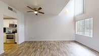 Located at 5917 N Oracle Rd in Tucson, Arizona, this two-story residence is thoughtfully laid out across two levels. The ground floor features an open living area with warm wood-look plank flooring, soaring vaulted ceilings, and large windows that invite abundant natural light. A striking spiral staircase with a sleek metal railing serves as both a functional and architectural centerpiece. The ceiling fan adds comfort suited to the Arizona climate. The galley-style kitchen is efficiently designed with white cabinetry, granite-look countertops, a stainless steel sink, dishwasher, refrigerator, and range, complemented by wood-look flooring that carries through from the main living area. A hallway connects to the bathroom, which features a full tub-shower combination with clean white surround and brushed nickel fixtures. Ascending to the upper level, a carpeted loft-style space is bright and airy, with a window overlooking the surroundings and open railing that overlooks the stairwell. A spacious walk-in closet on this floor offers built-in shelving, dual hanging rods, and carpeted flooring beneath a bold yellow ceiling accent, providing generous storage. The overall aesthetic is clean and neutral, presenting a functional and comfortable two-level living environment.