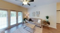 This single-floor residence offers a thoughtfully designed layout with a clean, contemporary aesthetic throughout. The kitchen is a functional highlight, featuring white shaker cabinetry extending to the ceiling, granite countertops, stainless steel appliances including a refrigerator, range, and dishwasher, and pendant lighting over the counter. Track lighting and wood-look flooring complete the space, which also provides direct access to an in-unit laundry closet with a full-size washer. A separate dining area accommodates a full dining set beneath an elegant chandelier, with wood-look flooring continuing seamlessly from the kitchen.

The living room is bright and inviting, with natural light pouring through a set of large glass patio doors that lead to an outdoor area. A ceiling fan adds comfort to the space. The bedrooms are carpeted and serene, each equipped with ceiling fans and natural light from windows. One bedroom features an en-suite bathroom with a glass-enclosed walk-in shower and granite vanity. Additional bathrooms include white cabinetry with granite countertops and tile flooring. The overall palette is neutral and cohesive, creating a calm, livable atmosphere throughout.