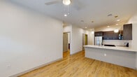 Located at 2136 Central Ave in Indianapolis, Indiana, this well-appointed two-bedroom, one-bathroom residence offers a clean, modern aesthetic with thoughtful design throughout. Light hardwood flooring flows seamlessly across the entire single-floor layout, creating a cohesive and airy feel.

The open-concept kitchen and living area serves as the heart of the home. The kitchen is outfitted with rich dark cabinetry, stainless steel appliances including a refrigerator, range, microwave, and dishwasher, and a white quartz countertop with a peninsula that doubles as a breakfast bar. Pendant lighting accents the space, while recessed lighting provides even illumination throughout.

A bright hallway connects the common areas to the private bedrooms. The primary bedroom offers a comfortable footprint with a ceiling fan, generous natural light, and direct access to a walk-in closet with built-in shelving and hanging rods. The second bedroom features a sliding-door closet with double hanging storage.

The full bathroom is finished with wood-look tile flooring, a tub-shower combination with large-format tile surround, a floating wood vanity with a white countertop, and a wide mirror.

A dedicated laundry room houses a full-size front-loading washer and dryer. The unit also benefits from a smart thermostat and outdoor access from the living area.