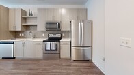 Located at 2700 E College Ave in Decatur, GA, this thoughtfully designed one-bedroom, one-bathroom unit offers a functional and modern living experience across a single floor. The open-concept layout seamlessly combines the kitchen, dining, and living areas into one cohesive space, maximizing efficiency without sacrificing comfort. Wood-look plank flooring runs throughout, providing warmth and visual continuity across the entire unit. The kitchen is well-appointed with light wood cabinetry, a decorative tile backsplash in a geometric pattern, white quartz-style countertops, and a full suite of stainless steel appliances including a French door refrigerator, electric range, over-the-range microwave, and dishwasher. The living area benefits from natural light through a large window. The bedroom is a comfortable size, featuring wood-look flooring, a large window with outdoor views, and easy access to a dedicated closet. The bathroom is finished with neutral tile flooring, a wood-toned vanity with an undermount sink, a large framed mirror, and clean white fixtures. Additional conveniences include an in-unit laundry area and a private patio, rounding out this well-equipped and contemporary Decatur residence.