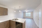 Located at 1455 Castle Manor Dr in Lincoln, Illinois, this single-floor, 2-bedroom, 1-bathroom residence offers a practical and comfortable layout. The open-concept kitchen and living area serves as the heart of the home, featuring warm-toned cabinetry, white countertops, a peninsula with an integrated double sink and pendant lighting overhead, and black appliances including a refrigerator, range, microwave, and dishwasher. Light wood-style flooring runs throughout the main living space, complementing the bright, neutral color palette. A ceiling fan in the living area adds to the comfortable ambiance, while a window brings in natural light.

Both bedrooms are carpeted and feature ceiling fans, windows with blinds for natural light and privacy, and access to closets. The primary bedroom offers a generous footprint with two doorways providing convenient access. The full bathroom is equipped with a tub-shower combination, brushed nickel grab bars, and wood-style flooring. Additional practical spaces include a pantry, a utility room, a hallway, and five closets distributed throughout, ensuring abundant storage. The clean, neutral finishes and thoughtful layout make this a functional and inviting residence.