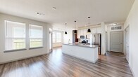 Located in Baytown, TX, this thoughtfully designed single-story residence offers three bedrooms, three bathrooms, and a well-organized floor plan that maximizes comfort and functionality. Light wood-look flooring runs through the main living areas, creating a clean, contemporary aesthetic that flows seamlessly from room to room.

The open-concept kitchen is a standout feature, anchored by a granite-topped island with a double undermount sink and stylish pendant lighting. White upper cabinetry contrasts elegantly with dark wood lower cabinets, while stainless steel appliances — including a French door refrigerator, electric range, and over-the-range microwave — complete the modern look. The kitchen connects naturally to the dining and living areas, which are bathed in natural light from multiple windows offering views of the surrounding greenery.

The bedrooms offer a mix of soft carpeting and wood-look flooring. Several rooms feature large windows with outdoor views, and the primary bedroom includes a ceiling fan for added comfort. Each bedroom is supported by its own closet, and three full bathrooms serve the home — one showcasing a granite vanity with gold hardware and a tiled soaking tub surround. A dedicated laundry space with a full-size washer and dryer rounds out this well-appointed home.