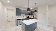 Located at 888 Horizon Boulevard in Athens, GA, this well-appointed 2-bedroom, 2-bathroom single-story home offers a thoughtfully designed layout with modern finishes throughout. The open-concept kitchen and living area serves as the heart of the home, showcasing slate-blue shaker cabinets with gold hardware, crisp white quartz countertops, a subway tile backsplash, and a central island with pendant lighting. Stainless steel appliances complete the kitchen's polished, contemporary look. Marble-look tile flooring flows through the kitchen and wet areas, while light hardwood-style flooring carries through the living spaces and bedrooms. The living room features a bold navy accent wall and a ceiling fan, with a glass door opening to an outdoor deck. Both bedrooms are highlighted by striking shiplap accent walls, ceiling fans, and recessed lighting. The primary bedroom is generously sized and includes a walk-in closet with wire shelving. Each bathroom is finished with coordinating slate-blue vanities, marble-look tile floors, and white subway tile tub surrounds with matte black fixtures. A dedicated laundry room includes a full-size washer and dryer. A hallway with a sliding barn-style door connects the spaces, and two well-organized closets provide ample storage throughout the home.
