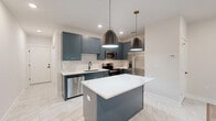 Located at 888 Horizon Boulevard in Athens, GA, this well-appointed 2-bedroom, 2-bathroom single-story home offers a thoughtfully designed layout with modern finishes throughout. The open-concept kitchen and living area serves as the heart of the home, showcasing slate-blue shaker cabinets with gold hardware, crisp white quartz countertops, a subway tile backsplash, and a central island with pendant lighting. Stainless steel appliances complete the kitchen's polished, contemporary look. Marble-look tile flooring flows through the kitchen and wet areas, while light hardwood-style flooring carries through the living spaces and bedrooms. The living room features a bold navy accent wall and a ceiling fan, with a glass door opening to an outdoor deck. Both bedrooms are highlighted by striking shiplap accent walls, ceiling fans, and recessed lighting. The primary bedroom is generously sized and includes a walk-in closet with wire shelving. Each bathroom is finished with coordinating slate-blue vanities, marble-look tile floors, and white subway tile tub surrounds with matte black fixtures. A dedicated laundry room includes a full-size washer and dryer. A hallway with a sliding barn-style door connects the spaces, and two well-organized closets provide ample storage throughout the home.
