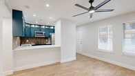 This thoughtfully designed single-floor residence offers three bedrooms, one bathroom, a pantry, and dedicated closets, all connected by a central hallway. Light wood-tone flooring runs throughout, creating a cohesive and clean aesthetic across every room.

The open living area is anchored by a modern ceiling fan with integrated lighting and recessed lights overhead, giving the space a bright, airy feel. Natural light enters through windows fitted with blinds, and a front entry door provides a welcoming focal point.

The kitchen is a standout feature, showcasing rich teal cabinetry that extends to the ceiling with glass-panel upper accents and a distinctive vertical slat backsplash. Stainless steel appliances — including a refrigerator, microwave, and dishwasher — complement the crisp white countertops. A peninsula counter opens toward the living space, enhancing functionality and flow. A pantry provides additional storage nearby.

Each bedroom benefits from ceiling fans, recessed lighting, and light wood flooring. The spacious primary bedroom includes dual windows for natural light, while another bedroom features a large sliding door covered by vertical blinds.

The bathroom is finished with large-format tile in the tub surround, matte black fixtures, and teal cabinetry overhead, tying the design language together throughout the home.