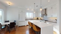 Located at 422 E Boston Post Rd in Mamaroneck, NY, this thoughtfully designed 3-bedroom, 3-bathroom single-floor residence combines modern finishes with a bright, open layout. Rich hardwood flooring flows throughout, tying together a cohesive and refined aesthetic.

The gourmet kitchen is a standout feature, showcasing crisp white shaker cabinetry extending to the ceiling, grey quartz countertops, a subway tile backsplash, and a professional-grade stainless steel range with a wall-mounted hood. A large center island with seating provides both function and casual dining. Pendant lighting and recessed fixtures illuminate the space, while a window above the sink frames views of the marina beyond.

The living room is anchored by a sleek fireplace with a classic white surround, above which a wall-mounted television is installed. Large windows and sliding glass doors flood the room with natural light and offer picturesque views of the surrounding marina and waterfront.

Three well-proportioned bedrooms provide comfortable retreats, each with hardwood floors and generous natural light. The three bathrooms are finished in a clean, contemporary style, featuring floating vanities with white countertops, herringbone and neutral tile flooring, and polished chrome fixtures. The overall ambiance of the residence is bright, modern, and serene.