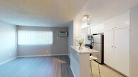 Located on Weddington Street in the Sherman Oaks neighborhood of Los Angeles, this single-floor unit offers a thoughtfully designed layout with a seamless flow between living and kitchen spaces. The open-concept kitchen is equipped with stainless steel appliances — including a refrigerator, gas range, and microwave — complemented by crisp white cabinetry that extends to the ceiling for ample storage. A peninsula with a light stone-style countertop provides casual seating and serves as a natural divide between the kitchen and the living area. The living space features warm wood-look laminate flooring, neutral gray walls, and a large window dressed with vertical blinds that allows natural light to fill the room. A wall-mounted air conditioning unit ensures year-round comfort. A hallway connects the living area to the private quarters, where the bedroom showcases floor-to-ceiling mirrored sliding closet doors, warm flooring, and a connected vanity area with a dual-sink white cabinet and well-lit mirror. The bathroom is cleanly appointed with a shower/tub combination, a single vanity with granite-style countertop, and wood-look flooring. The textured ceilings are consistent throughout, lending the space a classic residential character. Track lighting provides focused illumination in key areas throughout the unit.