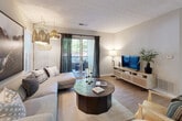 This single-floor residence offers a thoughtfully designed open-concept layout finished with light hardwood-style flooring and neutral gray walls throughout. The kitchen is equipped with white cabinetry, a subway tile backsplash, stainless steel appliances, and a peninsula with a dark countertop that accommodates bar seating — ideal for casual dining or entertaining. Adjacent to the kitchen, a dedicated dining area features recessed lighting, wainscoting-style wall detailing, and a barn-style pass-through mirror that adds visual depth to the space.

The living room is generously proportioned and anchored by a sliding glass door that opens onto a private balcony with outdoor views of surrounding greenery, allowing natural light to fill the room. The bedrooms offer comfortable retreats, each with hardwood-style flooring, large windows, and ceiling fans. The bathroom includes a full tub-shower combination with white tile surround. A dedicated laundry area provides in-unit convenience with full-size washer hookups and overhead shelving. Together, these elements create a cohesive, well-appointed living environment with a clean, contemporary aesthetic.