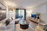This single-floor residence offers a thoughtfully designed open-concept layout finished with light hardwood-style flooring and neutral gray walls throughout. The kitchen is equipped with white cabinetry, a subway tile backsplash, stainless steel appliances, and a peninsula with a dark countertop that accommodates bar seating — ideal for casual dining or entertaining. Adjacent to the kitchen, a dedicated dining area features recessed lighting, wainscoting-style wall detailing, and a barn-style pass-through mirror that adds visual depth to the space.

The living room is generously proportioned and anchored by a sliding glass door that opens onto a private balcony with outdoor views of surrounding greenery, allowing natural light to fill the room. The bedrooms offer comfortable retreats, each with hardwood-style flooring, large windows, and ceiling fans. The bathroom includes a full tub-shower combination with white tile surround. A dedicated laundry area provides in-unit convenience with full-size washer hookups and overhead shelving. Together, these elements create a cohesive, well-appointed living environment with a clean, contemporary aesthetic.