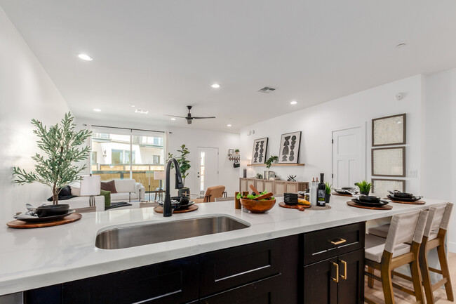 Cocina comedor con encimeras de mármol blanco y negro y gabinetes negros. - The CJ Luxury Townhomes