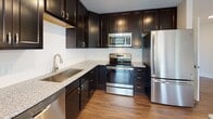 Located at 45 Sayles Hill Rd in North Smithfield, Rhode Island, this single-floor unit offers a well-designed layout with contemporary finishes throughout. The open living area features rich hardwood flooring and large windows that invite generous natural light, with direct access to a private balcony overlooking lush, mature trees — creating a bright and serene atmosphere.

The kitchen is outfitted with dark espresso cabinetry extending to the ceiling for ample storage, light granite countertops, a white subway tile backsplash, and a full suite of stainless steel appliances including a refrigerator, range, built-in microwave, and dishwasher. Warm hardwood flooring ties the kitchen seamlessly to the main living space.

The bedroom is generously proportioned, featuring plush carpeting and a trio of windows that frame views of the surrounding greenery, providing a calm and comfortable retreat.

The bathroom showcases a classic black-and-white mosaic tile floor, a dark double-sink vanity with a white countertop, a large mirror, and well-placed lighting — combining timeless style with practical functionality.

Overall, the space presents a clean, modern aesthetic with quality materials, abundant natural light, and thoughtful design details throughout.