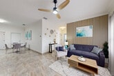 Located at 171 24th St in Cocoa Beach, Florida, this thoughtfully designed 2-bedroom, 2-bathroom unit offers a cohesive blend of coastal charm and contemporary style across a well-utilized single floor.

The living room serves as the centerpiece of the space, highlighted by a striking vertical slatted wood accent wall, a modern ceiling fan, crown molding, and large-format tile flooring that extends throughout the unit. Natural light filters in through sheer-curtained windows, enhancing the bright, airy atmosphere.

The kitchen features white shaker cabinetry with gold hardware, dark countertops, and stainless steel appliances, creating a clean and functional workspace that opens to the dining area.

The primary bedroom is a serene retreat, showcasing a geometric panel accent wall, a statement crystal chandelier, and soft natural light from a large window dressed in sheer curtains. The second bedroom is bright and versatile, with neutral tones and modern abstract wall art.

Both bathrooms are well-appointed, with one featuring a spacious walk-in glass-enclosed shower with floor-to-ceiling tile surround. A dedicated in-unit laundry room with overhead cabinetry and gold hardware adds everyday convenience. The hallway connects all areas with a clean, streamlined flow throughout the home.