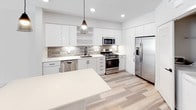 Located at 1921 Union St in Anaheim, California, this modern single-story residence showcases a clean, contemporary design throughout. Light-toned luxury vinyl plank flooring flows across the main living areas, complementing a bright, neutral color palette that creates an airy and welcoming atmosphere.

The kitchen is a standout feature, outfitted with high-gloss white cabinetry extending to the ceiling, a textured tile backsplash, and a full suite of stainless steel appliances including a gas range, built-in microwave, dishwasher, and a French door refrigerator. A large quartz island anchors the space, while recessed lighting and a pendant light above add both task and ambient illumination.

The bedrooms are finished with plush neutral carpeting and feature ceiling fans with lighting. The primary bedroom includes direct access to a walk-in closet and an en-suite bathroom, while additional rooms offer generous proportions and natural light through slatted window blinds.

The bathroom is appointed with a dual-sink vanity topped with a white quartz countertop, matte black fixtures, and large frameless mirrors accompanied by modern wall-mounted lighting. Frosted glass door panels add a refined architectural touch. The overall design reflects a cohesive modern aesthetic with quality finishes throughout.