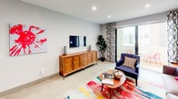 This contemporary single-floor residence offers a thoughtfully designed layout with a cohesive modern aesthetic throughout. The living area is bright and welcoming, featuring neutral gray walls, recessed lighting, polished concrete-style flooring, and a sliding glass door that opens to a private balcony with urban views. A warm wood media console anchors the room, complemented by a vibrant multicolored area rug and bold abstract wall art that add a lively, creative energy to the space.

An adjacent lounge area is defined by a striking deep-blue accent wall, creating a cozy and sophisticated atmosphere. The kitchen is efficiently appointed with stainless steel appliances, including a gas range and built-in microwave, wood-grain lower cabinetry, high-gloss upper cabinets, a white subway tile backsplash, and quartz countertops with an undermount sink.

The bedroom is generously proportioned, featuring a ceiling fan, a bold geometric red accent wall, a built-in closet with shelving, and its own sliding glass door opening to the balcony. The full bathroom showcases a deep-blue accent wall, a backlit vanity mirror, wood-tone cabinetry, and a soaking tub with shower combo. A dedicated in-unit laundry closet with stacked washer and dryer adds everyday convenience to this well-appointed residence.