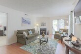 This single-story residence at 388 S Military Hwy in Norfolk, Virginia offers a well-organized layout with a comfortable mix of functional and inviting living spaces. The living room serves as the central gathering area, featuring warm hardwood-style flooring, a textured ceiling, and natural light streaming through windows with sheer curtains. A standout fireplace with a clean surround anchors one wall, while a sliding glass door provides direct access to a private balcony overlooking greenery.

The kitchen is fully equipped with honey-toned wood cabinetry, dark granite-style countertops, and black appliances including a range, microwave, and dishwasher, all set over durable hardwood-style flooring. A dedicated laundry area houses a full-sized side-by-side washer and dryer with overhead shelving for added storage convenience.

The bedrooms are carpeted and generously sized, each offering natural light through double-hung windows. One bedroom features walk-in closet access. The bathrooms include tub-shower combinations with clean white fixtures; one features granite-style countertops with wood cabinetry. Throughout the unit, neutral tones create a cohesive and move-in-ready atmosphere.
