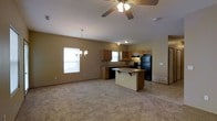 This multi-story home spans three floors, offering generous living space across each level. The main floor showcases an open-concept layout that seamlessly connects the living area to the kitchen, creating an inviting and functional environment. The kitchen is equipped with warm wood-toned cabinetry, a black refrigerator and range, an under-cabinet range hood, and a center island with bar-style seating — ideal for casual dining or meal prep. A double sink sits beneath a window, allowing natural light to brighten the workspace. The adjoining living area features plush wall-to-wall carpeting, lending a cozy atmosphere throughout. Vaulted or angled ceilings add a sense of openness and volume to the main floor, complemented by a ceiling fan for year-round comfort. An elegant chandelier pendant light hangs near the dining area, adding a refined touch to the space. Neutral wall tones throughout provide a versatile backdrop suitable for a variety of interior styles. The additional floors of the home offer further living, sleeping, or recreational space, making this a well-rounded property suited for a range of lifestyles and household sizes.