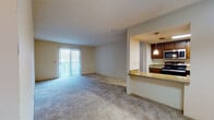 This single-floor, 2-bedroom, 2-bathroom residence is thoughtfully laid out for comfortable everyday living. The open-concept living area is anchored by soft carpeting and a large sliding glass door fitted with vertical blinds, allowing generous natural light to fill the space. A pass-through opening connects the living area to the kitchen, creating a seamless flow between the two spaces.

The galley-style kitchen features warm wood cabinetry, light countertops, and stainless steel appliances including a refrigerator, range, and over-the-range microwave. Hardwood-style flooring and a pendant light fixture add warmth and functionality to this efficient cooking space.

Both bedrooms are carpeted and well-sized, each offering windows for natural light. One bedroom includes a mirrored sliding closet door, while the other benefits from its own sliding glass door. The bedrooms provide access to the two bathrooms, each finished with wood vanity cabinetry, a single-sink countertop, a large mirror with vanity lighting, and tile flooring.

Additional highlights include in-unit washer and dryer hookups, textured ceilings throughout, and a practical layout that maximizes the use of available space across the entire residence.