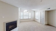 This single-floor, one-bedroom, one-bathroom residence in Collierville, Tennessee offers a well-organized layout designed for comfortable everyday living. The living area serves as the focal point of the home, featuring vaulted ceilings that enhance the sense of openness, a ceiling fan with light fixture, and a wall fireplace with a sleek black surround. A prominent arched window flanked by additional standard windows floods the space with natural light, while plush wall-to-wall carpeting adds warmth underfoot. A textured ceiling is consistent throughout the living and bedroom areas.

The galley-style kitchen is efficiently designed, offering light wood-tone flooring, gray cabinetry with updated hardware, granite-style countertops, and a full suite of black appliances including an electric range, microwave, and refrigerator. A passthrough counter connects the kitchen to the living area, creating an open, connected feel.

The bedroom is a well-proportioned, carpeted room featuring its own ceiling fan, neutral walls, and a six-panel door. An adjacent hallway leads directly to the bathroom. The overall color palette throughout is a consistent warm neutral, lending the space a clean, cohesive appearance.