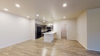 This well-appointed single-floor residence offers a thoughtfully designed open-concept layout that seamlessly connects the living and kitchen areas. The kitchen is a standout feature, equipped with dark wood-tone cabinetry, white countertops, a tile backsplash, black appliances including a full-size refrigerator, electric range, and built-in microwave, as well as a kitchen island with a built-in sink. Recessed and pendant lighting illuminate the space, while track lighting adds a modern touch. Light wood-look flooring extends throughout the main living areas and hallways, creating a cohesive and clean aesthetic.

The living area is generously proportioned, featuring a ceiling fan and access to additional rooms via a hallway. The bedrooms are finished with plush carpeting, ceiling fans, and windows fitted with blinds that allow for natural light while maintaining privacy.

Two bathrooms serve the residence — one featuring a full tub-shower combination with white fixtures and a dark-toned vanity with a white countertop, and a second bathroom with a walk-in glass-door shower, matching dark cabinetry, and ample counter space. Both bathrooms continue the wood-look flooring found throughout the home. Overall, the space presents a clean, contemporary aesthetic with consistent finishes throughout.