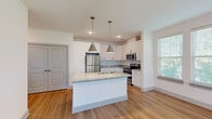 Located at 8251 Windsor Hill Blvd in North Charleston, SC, this single-floor, 2-bedroom, 1-bathroom residence offers a clean, contemporary design with thoughtful finishes throughout. The open-concept kitchen and living area serves as the heart of the home, centered around a granite-topped island with a undermount sink and stylish pendant lighting. White shaker cabinetry, a tile backsplash, and a full suite of stainless steel appliances — including a refrigerator, range, and microwave — complete the well-appointed kitchen. Light wood-look flooring flows seamlessly through the main living areas, enhancing the bright, airy atmosphere. The living room benefits from a wall of large windows fitted with blinds, inviting abundant natural light and tree-lined outdoor views. The primary bedroom offers comfortable carpeting and a spacious walk-in closet with built-in wire shelving for ample storage. A secondary bedroom includes access to an outdoor balcony with exterior views. The full bathroom features light wood flooring, a granite-topped vanity with white cabinetry, a tiled tub-shower combination, and a large mirror. Overall, the space presents a fresh, modern aesthetic suited for comfortable everyday living.