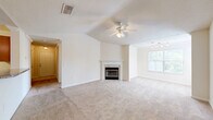 Located in Riverview, FL, this single-story 2-bedroom, 2-bathroom home offers a well-designed layout with notable architectural details throughout. The combined living and dining area serves as the heart of the home, featuring vaulted ceilings, a ceiling fan with light fixture, a classic fireplace with a white mantel, and a large window that brings in natural light. Neutral carpet and light-toned walls create a bright, welcoming ambiance throughout the main living areas. The kitchen is equipped with granite-style countertops, warm wood cabinetry, tile flooring, a tiled backsplash, and white GE appliances including an electric range, over-the-range microwave, and refrigerator. The primary bedroom is generously sized with vaulted ceilings, plush carpet, and access to a walk-in closet with wire shelving. The second bedroom features crown molding, a ceiling fan, carpet, and a window with natural light. Both bathrooms are clean and functional, with the second bath offering wood-look flooring, a tub-shower combo, and a vanity with a large mirror. A dedicated in-unit laundry room houses a full-size washer and dryer. The home also includes four closets, providing ample storage throughout.