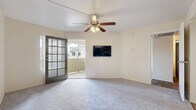 Located at 3443 E University Dr in Mesa, AZ, this single-story, one-bedroom, two-bathroom home offers a thoughtfully arranged layout that maximizes its compact footprint. The living room features plush carpeting, a ceiling fan with light fixture, and a charming French door that opens directly to the patio, filling the space with natural light and providing easy access to outdoor views of the surrounding landscape.

The kitchen is outfitted with warm wood-tone cabinetry, dark granite-style countertops, and black appliances including a range and refrigerator, all set over durable wood-look flooring. It connects conveniently to the dining area, creating a cohesive and functional common space.

The bedroom is generously sized with soft carpeting, a ceiling fan, and a sliding glass door leading to the patio, offering both natural light and a pleasant outdoor connection. Two closets provide ample storage throughout the unit.

Both bathrooms are finished with wood-look flooring and warm cabinetry with dark countertops. The primary bathroom features a wide vanity with dual mirrors, while the second bathroom includes a tub and shower combination. The overall palette of neutral tones and consistent finishes lends the home a clean, cohesive ambiance throughout.
