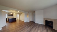 Located at 14615 NE Rose Pkwy in Portland, Oregon, this contemporary 3-floor home is thoughtfully designed with quality finishes throughout. The main living level features an open-concept layout with rich, dark hardwood-style flooring that flows seamlessly between the living area and kitchen. The spacious living room is bright and welcoming, with clean white walls, recessed lighting, and easy staircase access connecting all three floors. The kitchen is a standout, equipped with dark espresso cabinetry, stainless steel appliances including a gas range, microwave, dishwasher, and refrigerator, complemented by a granite-topped island and a window above the sink that brings in natural light. A powder room on the main level features a classic pedestal sink with an oval mirror. Additional bathrooms include a vanity with dark cabinetry, stone-look countertops, and tile backsplash detailing. The upper level offers carpeted bedrooms with windows providing natural light and exterior views. A well-lit hallway with carpeted stairs connects the floors smoothly. The lower level includes a generously sized attached garage with an automatic opener, fluorescent lighting, and a clean concrete floor, providing ample storage and parking space.
