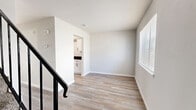 Located at 3727 S Lakewood Ave in Tulsa, Oklahoma, this two-story unit offers a practical and well-appointed layout across two floors. The main level features wood-style plank flooring that flows through an open living area and into the adjacent kitchen, which is equipped with stainless steel appliances including a refrigerator and gas range. Clean, neutral-toned walls and ample overhead ventilation give the living space a bright, airy feel. A convenient half bathroom with dark granite accents is also situated on the main floor. A staircase connects to the upper level, where both bedrooms are found, each outfitted with soft carpeting, ceiling fans, and windows with blinds that allow for natural light. The primary bedroom is generously proportioned and includes a dedicated closet with built-in shelving. The second bedroom features a double-door closet with matte black hardware, adding a contemporary touch. The full bathroom on the upper level showcases large-format marble-style tile surrounding a tub-shower combination, wood-look flooring, and sleek matte black fixtures. The hallway connects all upper-level rooms efficiently. Throughout the unit, the design emphasizes clean lines, neutral palettes, and functional finishes suited for comfortable everyday living.