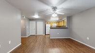 This single-story residence offers a practical and comfortable layout across two bedrooms and two bathrooms. The open-concept living and kitchen area serves as the heart of the unit, featuring warm wood-look flooring throughout and a ceiling fan with integrated lighting. The kitchen is efficiently designed with light wood cabinetry, dark countertops, white appliances including a refrigerator, stove, and microwave, and a peninsula breakfast bar that connects seamlessly to the living area — ideal for both meal prep and casual dining.

The bedrooms are carpeted for comfort and include ceiling fans, natural light from blinded windows, and generous closet storage. The primary bedroom features access to a spacious walk-in closet with built-in dual hanging rods and shelving. Additional bedrooms offer built-in closets with double doors and hardwood-style flooring.

The bathrooms are functionally appointed with wood-toned vanity cabinetry, dark countertops, large mirrors, and wood-look flooring. A hallway connects the private areas of the unit to the main living space. Neutral gray walls throughout create a cohesive, modern aesthetic that complements the warm flooring tones, making this a versatile and move-in-ready space.