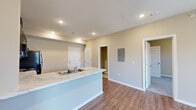 This single-floor unit offers a practical and well-appointed layout across two bedrooms and three bathrooms. The open-concept kitchen and living area forms the heart of the space, where wood-look plank flooring runs throughout. The kitchen features an L-shaped peninsula with a double-basin sink and marble-look countertops, paired with rich dark espresso cabinetry that extends to upper wall-mounted units. Black appliances, including a range, over-the-range microwave, dishwasher, and refrigerator, complete the functional cooking space. Recessed lighting illuminates the area, and sliding glass doors allow natural light to filter into the living zone.

The bedrooms are carpeted for comfort, with neutral-toned walls and windows fitted with blinds. The primary bedroom connects to its own bathroom, which features a dark vanity with a marble-look countertop, a large mirror, and a standalone walk-in shower. A second bathroom mirrors this consistent design aesthetic. Two closets provide dedicated storage, one of which includes wire shelving systems. The overall design maintains a cohesive, neutral palette throughout.