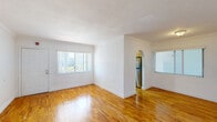 Located at 941 NE 169th St in North Miami Beach, FL, this one-bedroom, one-bathroom unit offers a well-organized layout across a single floor. Warm-toned hardwood flooring flows consistently throughout the living areas and bedroom, lending a cohesive and inviting character to the space. Crown molding accents the living room and bedroom ceilings, adding a classic architectural detail to the otherwise clean, white interior.

The living room is bright and open, featuring large windows with vertical blinds that allow abundant natural light while offering outdoor views of the surrounding greenery. An arched passageway connects the living area to the kitchen, which is equipped with light wood cabinetry, dark granite-style countertops, and ample storage on both sides of the galley-style layout.

The bedroom is a comfortable size, featuring a closet with bifold doors, crown molding, and continued hardwood flooring. Additional storage is accessible via a louvered closet door nearby.

The bathroom is finished with light tile flooring, a tub-shower combination enclosed by sliding glass doors, a vanity with a mirror, and tile accents along the shower walls. The overall design is clean and functional, making this a practical and well-appointed unit in the heart of North Miami Beach.