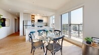 Located on Esquimalt Road in Victoria, BC, this well-appointed two-bedroom, two-bathroom unit offers a thoughtfully designed open-concept layout bathed in natural light. Large floor-to-ceiling windows in the living and dining area frame sweeping panoramic views of the surrounding Victoria cityscape and waterfront, creating a bright and airy atmosphere throughout.

The living area features light hardwood flooring that flows seamlessly into the dining space, where oversized windows continue to flood the room with sunlight. The modern kitchen is equipped with white cabinetry, a subway tile backsplash, stainless steel appliances including a full-size refrigerator, and a breakfast bar with seating — ideal for casual dining or entertaining.

Both bedrooms are comfortably sized with large windows that bring in natural light and offer outdoor views. The primary bedroom includes direct access to a balcony. The two bathrooms are finished with stone-effect tile; one features a soaker tub with tiled surround, while the other offers a glass-enclosed walk-in shower and warm wood-toned cabinetry with a white countertop vanity. A hallway connects the private areas of the unit, completing a functional and cohesive floor plan.