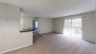 This single-floor residence at 9308 Willow Creek Dr in Montgomery Village, Maryland, offers a practical and comfortable layout with a clean, neutral aesthetic throughout. The open-concept living and dining area is generously proportioned, featuring plush wall-to-wall carpeting, soft neutral-toned walls, and a textured ceiling. A large sliding glass door floods the space with natural light and provides access to an outdoor balcony, offering views of surrounding greenery. The kitchen is efficiently designed with white cabinetry, dark granite-style countertops, a breakfast bar peninsula, and wood-look flooring. White appliances, including a range and refrigerator, complete the functional cooking space. A pendant light fixture adds a subtle decorative touch near the entry. The bedroom is a well-sized, carpeted retreat featuring a large window with vertical blinds that allow abundant natural light, along with a closet for ample storage. The bathrooms are clean and well-appointed; one features dark granite countertops, an undermount sink, a large vanity mirror, and a shower-tub combination, while the second offers a tub and wood-look flooring. The overall ambiance of this residence is bright, neutral, and move-in ready, providing a versatile canvas for personalization.