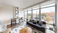 This single-floor residence offers a thoughtfully designed layout that balances modern aesthetics with functional living. The living room serves as the centerpiece of the unit, boasting expansive floor-to-ceiling windows that flood the space with natural light and provide sweeping views of the surrounding urban landscape. Light wood flooring, a geometric area rug, and contemporary furnishings contribute to the room's bright, stylish ambiance. A compact dining nook adjacent to the living area offers additional functionality without compromising the open feel of the space.

The galley-style kitchen is well-appointed with dark espresso cabinetry, stainless steel appliances including a refrigerator, range, microwave, and dishwasher, complemented by light quartz countertops and a vibrant mosaic tile backsplash. Track lighting overhead enhances both style and practicality.

The bedroom is a serene retreat featuring clean white walls, warm lighting, and direct access to a walk-in closet outfitted with built-in shelving and hanging storage. The full bathroom includes a tub-shower combination framed by grey tile surround, a dark vanity with quartz countertop, and recessed lighting, creating a polished, spa-like finish throughout.