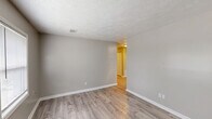 Located at 1800 Augusta Ct in Lexington, Kentucky, this single-floor, 3-bedroom, 1-bathroom home offers a practical and well-appointed layout. The living room greets you with a bold black front door, a large window that invites natural light, light wood-look flooring, and a textured ceiling — establishing a clean, neutral aesthetic carried throughout the home. The galley-style kitchen is efficiently designed with gray shaker cabinets, granite-look countertops, a double stainless steel sink, black appliances including an electric range and refrigerator, and overhead skylight-style lighting that brightens the workspace. Three bedrooms provide flexible living arrangements; the primary bedroom features light wood-look flooring and open access to the hallway, while the two additional bedrooms are carpeted and each include windows that bring in natural light. One bedroom benefits from dual windows, enhancing its airy feel. A closet with bi-fold doors is accessible from the hallway. The shared full bathroom is finished in crisp white with a tub-shower combination, a window for ventilation and natural light, gray vanity cabinetry, and matching wood-look flooring. A central hallway connects all rooms, creating a cohesive and easy-to-navigate floor plan throughout this compact yet functional home.
