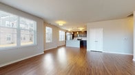 This well-appointed 1-bedroom apartment in Oak Creek, WI offers a thoughtfully designed single-floor layout that balances functionality with modern style. The open-concept living and dining area features rich hardwood-style flooring and large windows fitted with blinds, allowing ample natural light to fill the space. The kitchen is a standout feature, showcasing dark espresso cabinetry, white countertops, a center island with pendant lighting, and a full suite of stainless steel appliances including a refrigerator, electric range, and built-in microwave. The bedroom is carpeted for comfort and includes a spacious walk-in closet with built-in shelving and wire organizers. Two bathrooms serve the unit, each finished with dark wood vanities, white countertops, and hardwood-style flooring. The primary bathroom includes a glass-enclosed walk-in shower, while the second bathroom features a single-sink vanity. A dedicated in-unit laundry room houses a full-size side-by-side washer and dryer. Neutral tones throughout the unit create a clean, cohesive aesthetic suited for a variety of interior styles.