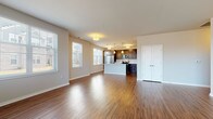 This well-appointed 1-bedroom apartment in Oak Creek, WI offers a thoughtfully designed single-floor layout that balances functionality with modern style. The open-concept living and dining area features rich hardwood-style flooring and large windows fitted with blinds, allowing ample natural light to fill the space. The kitchen is a standout feature, showcasing dark espresso cabinetry, white countertops, a center island with pendant lighting, and a full suite of stainless steel appliances including a refrigerator, electric range, and built-in microwave. The bedroom is carpeted for comfort and includes a spacious walk-in closet with built-in shelving and wire organizers. Two bathrooms serve the unit, each finished with dark wood vanities, white countertops, and hardwood-style flooring. The primary bathroom includes a glass-enclosed walk-in shower, while the second bathroom features a single-sink vanity. A dedicated in-unit laundry room houses a full-size side-by-side washer and dryer. Neutral tones throughout the unit create a clean, cohesive aesthetic suited for a variety of interior styles.