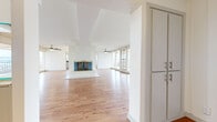 This well-appointed 2-bedroom, 2-bathroom residence occupies a single floor, offering a generous and thoughtfully laid-out living space. The open-concept living and dining area is a standout feature, anchored by a centrally positioned fireplace with a gold-trimmed surround and flanked by dual ceiling fans. Warm hardwood flooring flows throughout the main living areas, complementing the bright, white walls and clean architectural lines. A dramatic wall of floor-to-ceiling sliding glass doors spans the length of the living room, providing direct access to a wraparound balcony and framing expansive outdoor views, flooding the interior with natural light.

The kitchen is equipped with stainless steel appliances, white cabinetry, granite-style countertops, and a breakfast bar overhang, with an adjacent utility area featuring open shelving and additional storage. Both bedrooms are carpeted; the generously sized primary bedroom offers ample space, while the second bedroom includes built-in shelving. A dedicated closet provides additional storage. The bathrooms are finished with tile flooring, with one featuring a full shower-tub combination and a white vanity.
