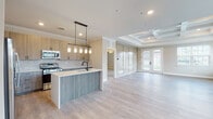 This single-floor residence showcases a thoughtfully designed open-concept layout that seamlessly connects the kitchen and living areas. The kitchen is a standout feature, equipped with stainless steel appliances including a gas range, microwave, and French door refrigerator. Light wood cabinetry pairs with a herringbone-patterned tile backsplash, while a two-tone island with a white quartz countertop and gray wood-look base provides additional prep space and seating. Pendant lights with glass shades hang above the island, adding a refined touch.

The living area features light hardwood-style flooring and a coffered tray ceiling that adds architectural depth. French doors allow natural light to fill the space and provide outdoor access. A separate carpeted room with its own tray ceiling and pendant light fixture offers flexibility as a bedroom or flex space.

The bathroom is finished with large-format tile flooring, a tub-shower combination accented by a mosaic tile inlay, a wood-tone vanity with white countertop, and matte black hardware throughout. A dedicated laundry room includes upper cabinetry, a utility sink, and hardwood-style flooring. The attached garage features an automatic opener and concrete flooring, completing this well-appointed home.