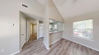 This one-bedroom, one-bathroom unit in Edinburg, Texas, offers a smartly designed single-floor layout that maximizes every square foot. The living area immediately impresses with striking vaulted ceilings that lend an open, airy feel well beyond the unit's compact footprint. Durable hardwood-style laminate flooring runs consistently throughout, tying the spaces together with a clean, modern aesthetic.

The kitchen is thoughtfully positioned behind a pass-through counter that opens to the living area, creating a connected and functional flow. White cabinetry, a matching white refrigerator, and an electric range provide a bright, cohesive look, while a window above the sink allows natural light to fill the space.

The bedroom offers a comfortable and private retreat, featuring a ceiling fan with light fixture, a window with outdoor views of surrounding greenery, and a tray ceiling detail that adds architectural character. A dedicated closet provides convenient built-in storage directly off the bedroom.

The bathroom is finished in neutral tones with a white vanity and stone-look countertop, a large mirror, a tub/shower combination, and a window that introduces additional natural light. Clean lines and practical fixtures make the space both functional and inviting. Overall, this unit presents a well-maintained, efficient living space with thoughtful design details throughout.